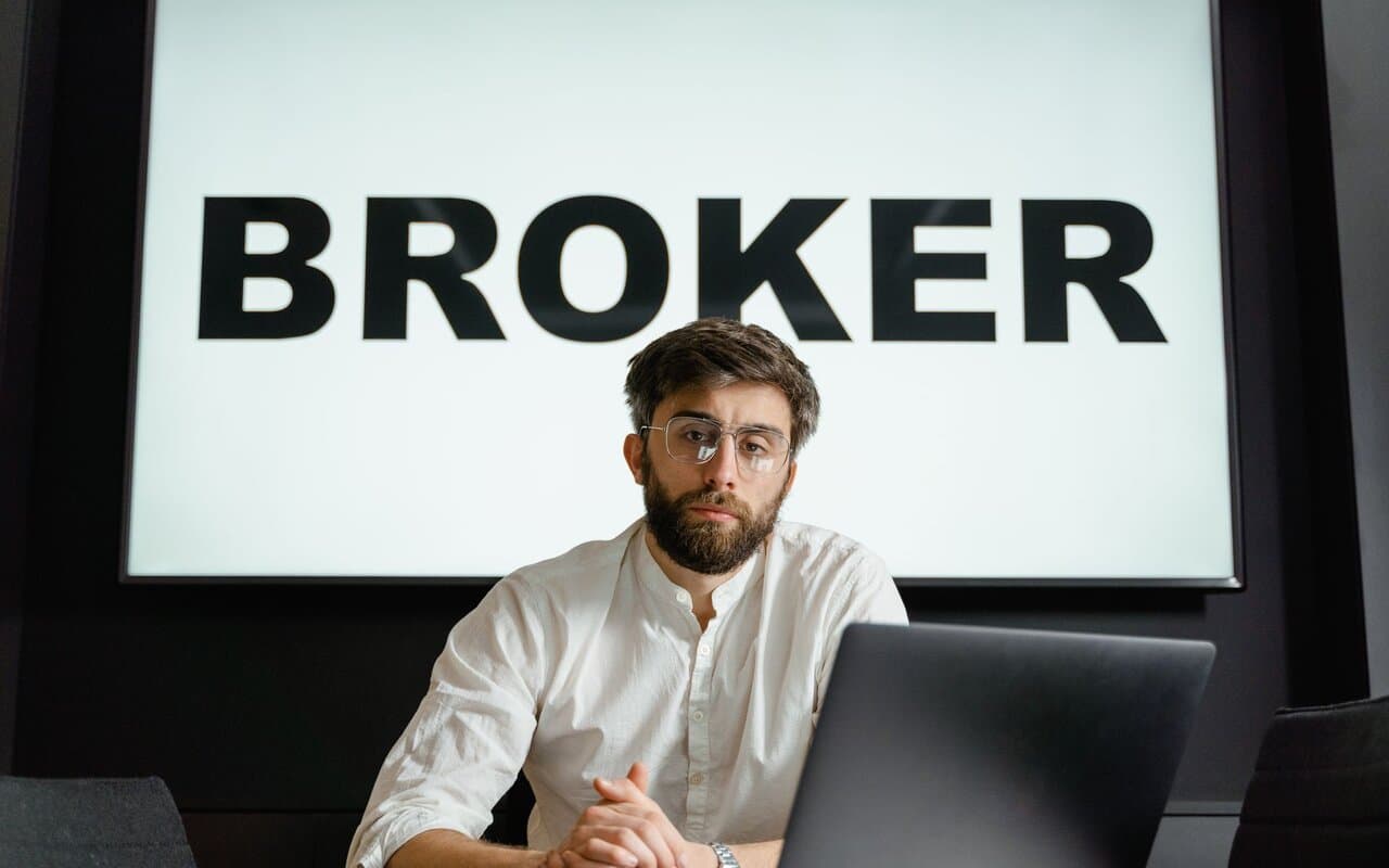 Professional reviewing trading data on a laptop in a broker office
