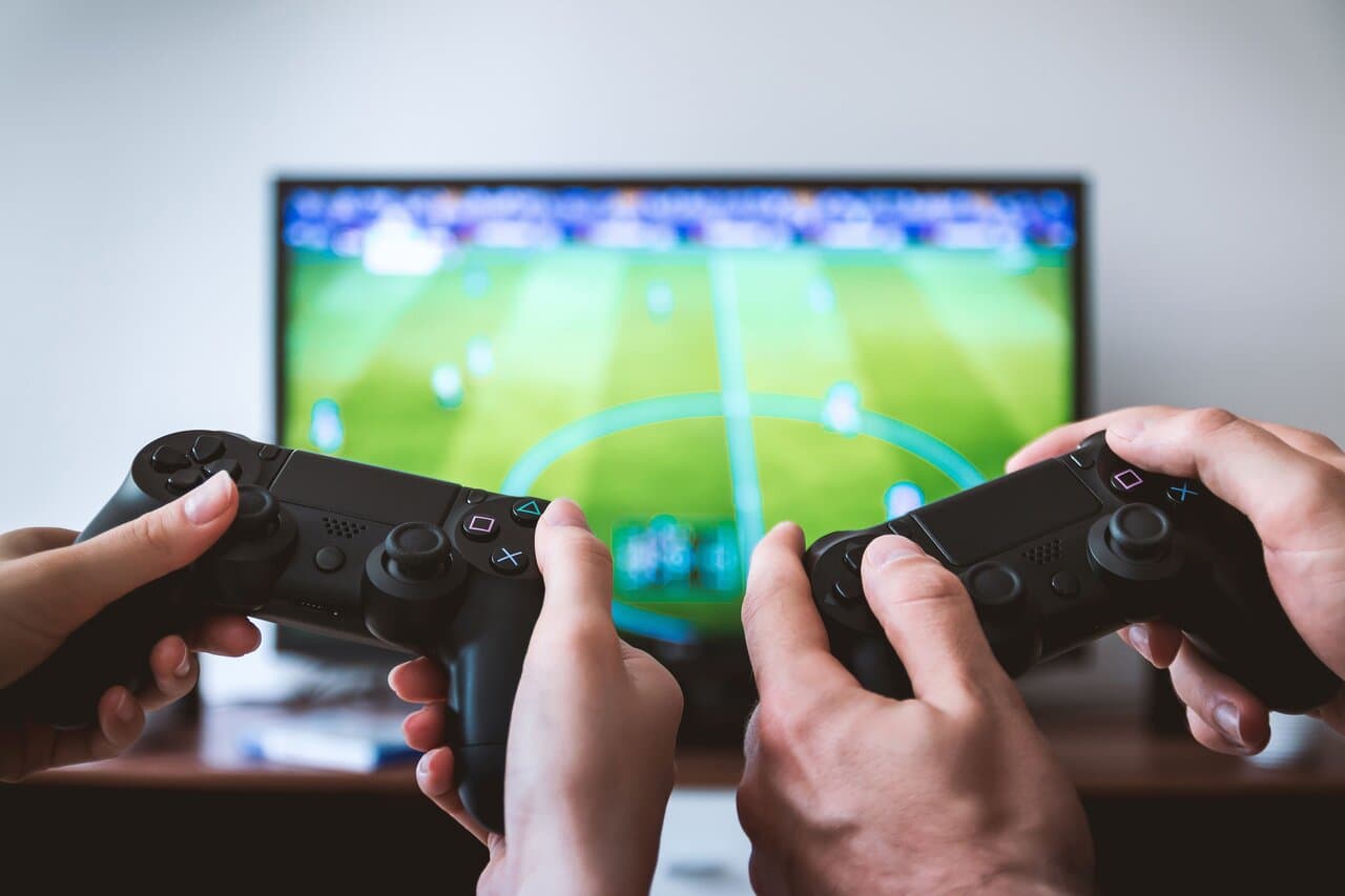 Two players holding game controllers while playing on a console